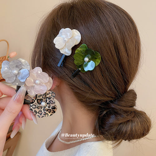 Green and cream resin flower clips worn in bun with three more held