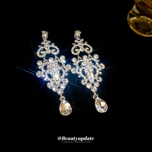 silver tone ornate openwork crystal teardrop earrings displayed from a second angle