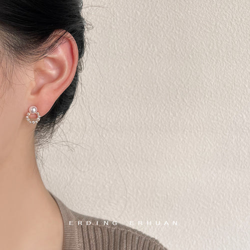 Gold-tone pearl-like floral-wreath studs shown worn on an ear.