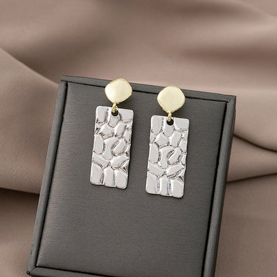 Gold disc silver hammered rectangle drop earrings on gray display pad