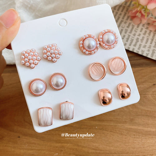 Rose gold six pair pearl shell metal stud earring card held over wood table