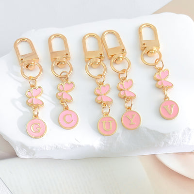 Row of five keychains with pink enamel butterflies and round initial letter discs on gold swivel clasps
