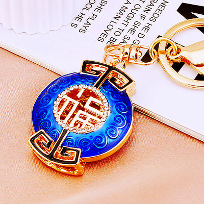 A styled product view shows the jeweled fortune plaque keychain and attached key hardware.