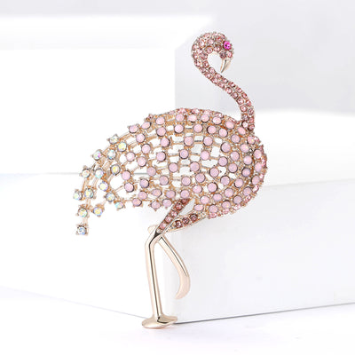 Front view of the pink crystal flamingo brooch showing a pale pink flamingo covered in crystals with a long gold-tone le