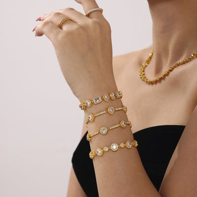 Model arm stacked with multiple gold zircon bracelets including round halo style