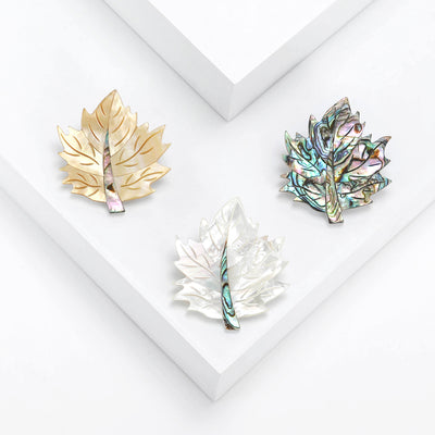 Three mother of pearl maple leaf brooches yellow white and abalone green