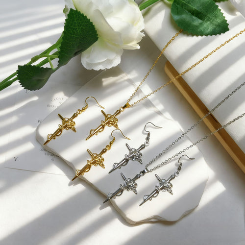 Gold and silver rose cross necklaces and earrings arranged on white heart tray