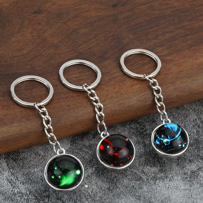 Three zodiac cabochon keychains with green, red and blue designs