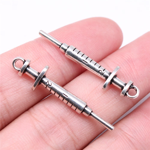 Close view of syringe-shaped connector charms in four metal finishes