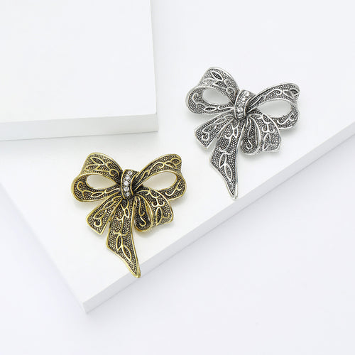 Angled display of the openwork ribbon bow brooch on a white surface
