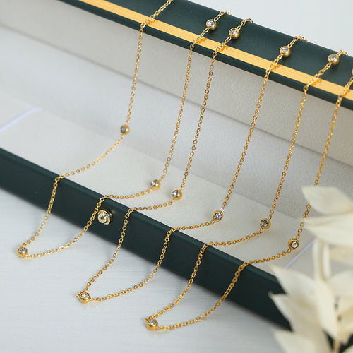 Multiple gold crystal station chains draped on green jewelry tray