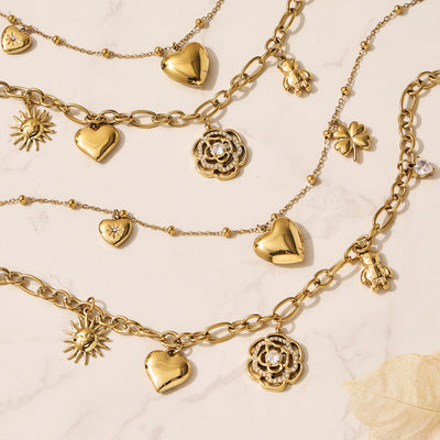 Gold multi-charm rose heart sun bear necklaces flat lay