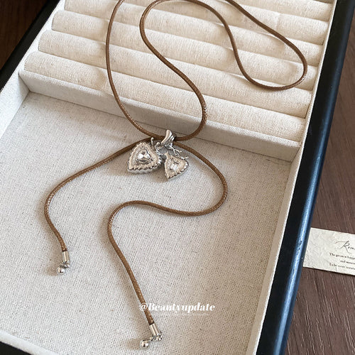 A small heart slider with two long fine chain tassels shown in a styled close-up