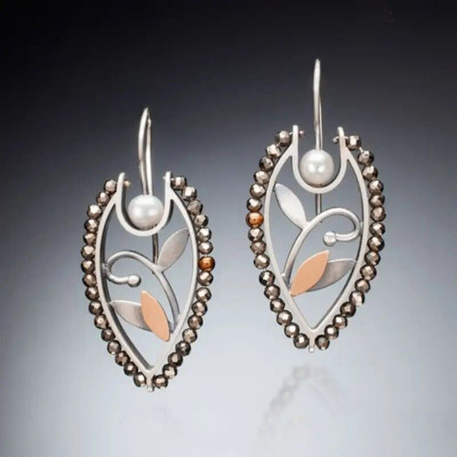 Pair of silver copper leaf teardrop earrings on dark gradient backdrop