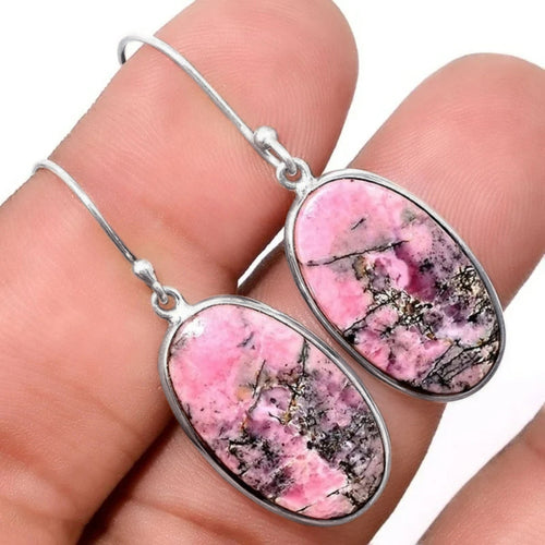 Antique silver pink mottled oval drop earrings held in fingers close-up