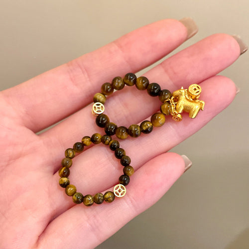 Tiger eye bead ring with gold horse pendant held in open palm