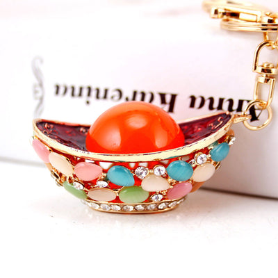 Front view of an ingot-shaped keychain decorated with an orange orb and multicolor oval accents.