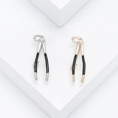 Silver Pliers, Gold Pliers brooch styles arranged on a light display