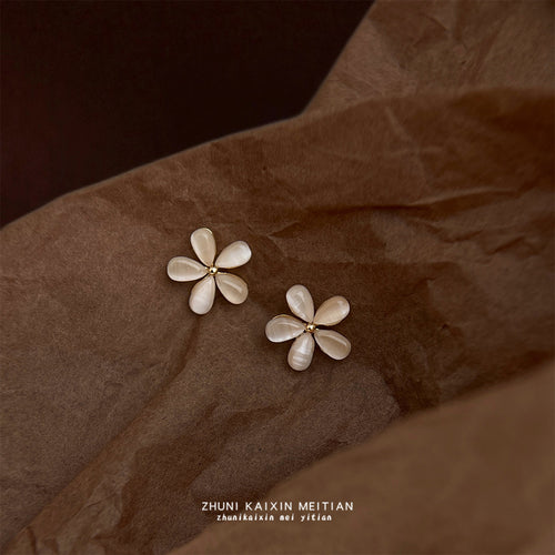 Cream cat eye five petal flower studs on crumpled brown paper