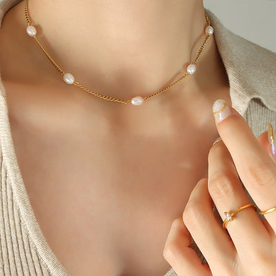 Gold curb chain pearl station necklace worn at collarbone