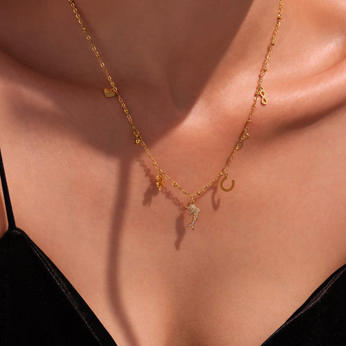 Close-up gold dolphin charm necklace with heart clover horseshoe drops