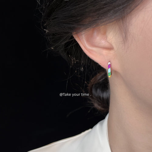 Model ear wearing rainbow enamel mini huggie hoop earring