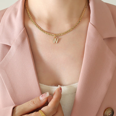 Gold rope chain W letter pendant necklace worn on pink blazer