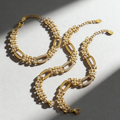 Three gold watch-band link bracelets with zircon ovals on white