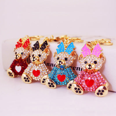 Four gold-tone bear keychains display red, clear, blue, and pink rhinestone bodies.