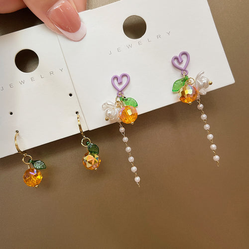 Gold hoop fruit drops beside purple heart pearl tassel pair