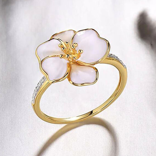 Gold white enamel flower ring soft-focus on white fabric
