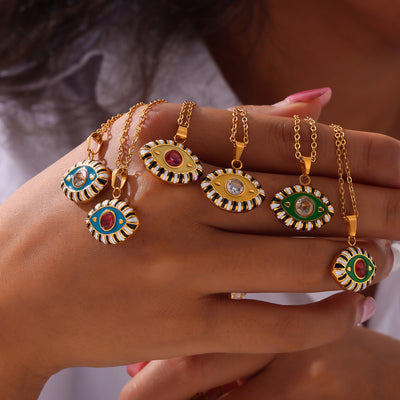Hand holding several gold enamel evil eye pendant necklaces