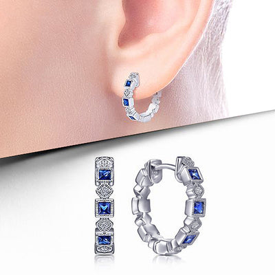 Front product view of silver tone hoop earrings with alternating blue and clear stones
