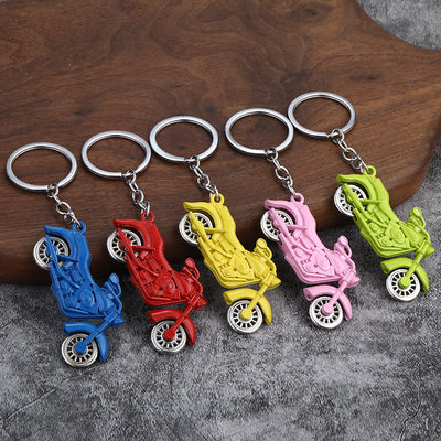 Five motorcycle keychains in blue, red, yellow, pink, and green on a gray surface.