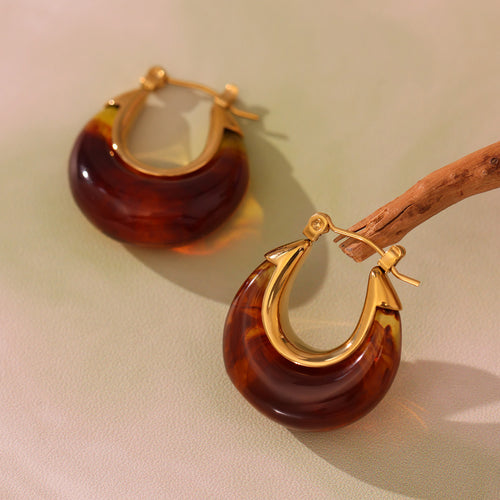 Close product pair of amber resin gold-frame U-hoop earrings