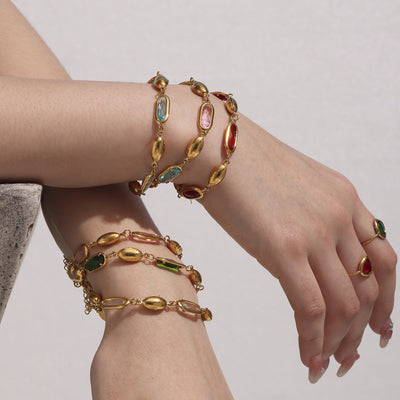 Model wrists stacked with multi-color gold oval Czech glass bracelets