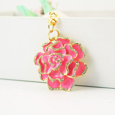 A pink layered rose charm hangs from gold-tone hardware against a white background.