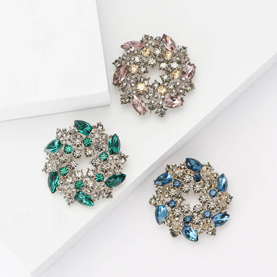 Grouped view of pink green and blue star wreath brooches arranged together.