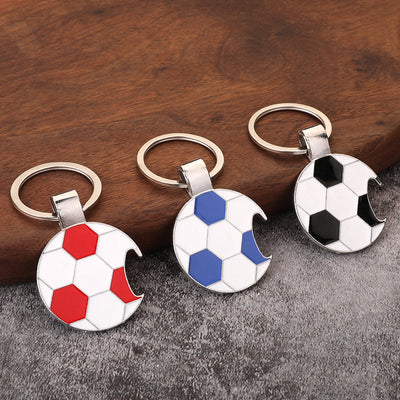 Three soccer ball bottle opener keychains in red, blue, and black on a tabletop.