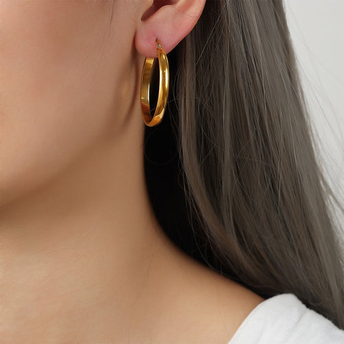 Model wearing large gold oval O-hoop earring side profile