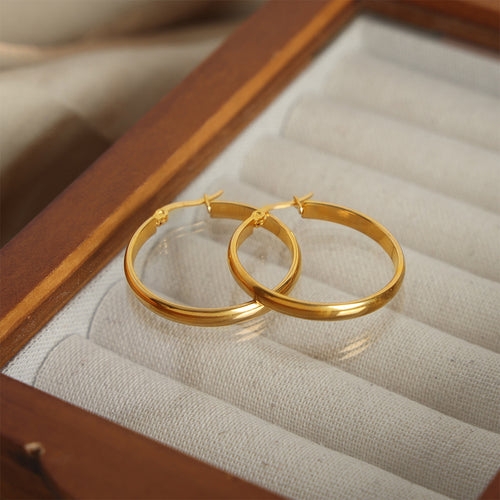 Pair of gold oval hoops nested in wood jewelry tray
