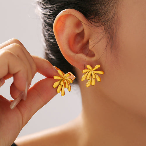 Gold firework petal stud earrings worn and held near ear