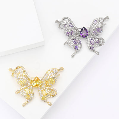 Purple and yellow crystal butterfly brooches on white geometric blocks