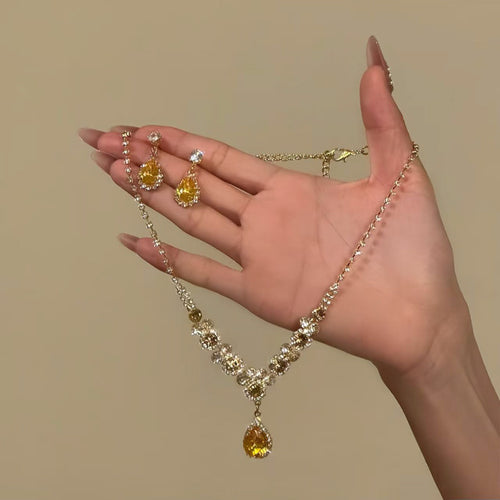 Gold yellow crystal necklace and earrings held in open hand