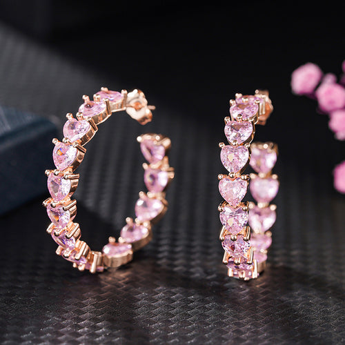 Pair of pink heart hoops standing on dark textured surface