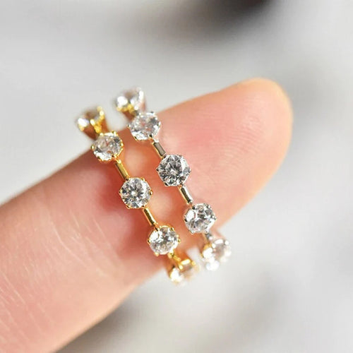 Gold and silver five stone station rings stacked on fingertip