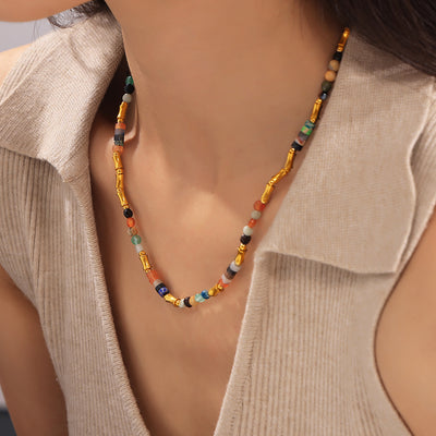 Woman wearing multicolor natural stone and gold bamboo bead necklace on collarbone