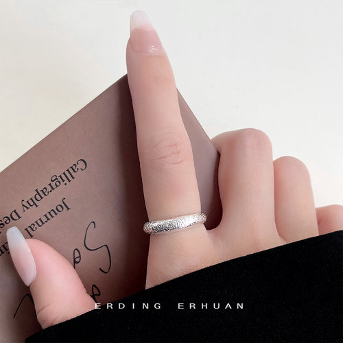 Silver frosted open band ring worn on index finger