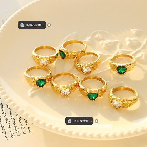 Group of gold heart glass stone rings on dish with material labels