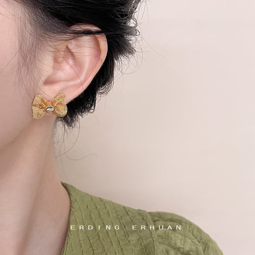 Gold mesh bow stud worn on left ear with green top